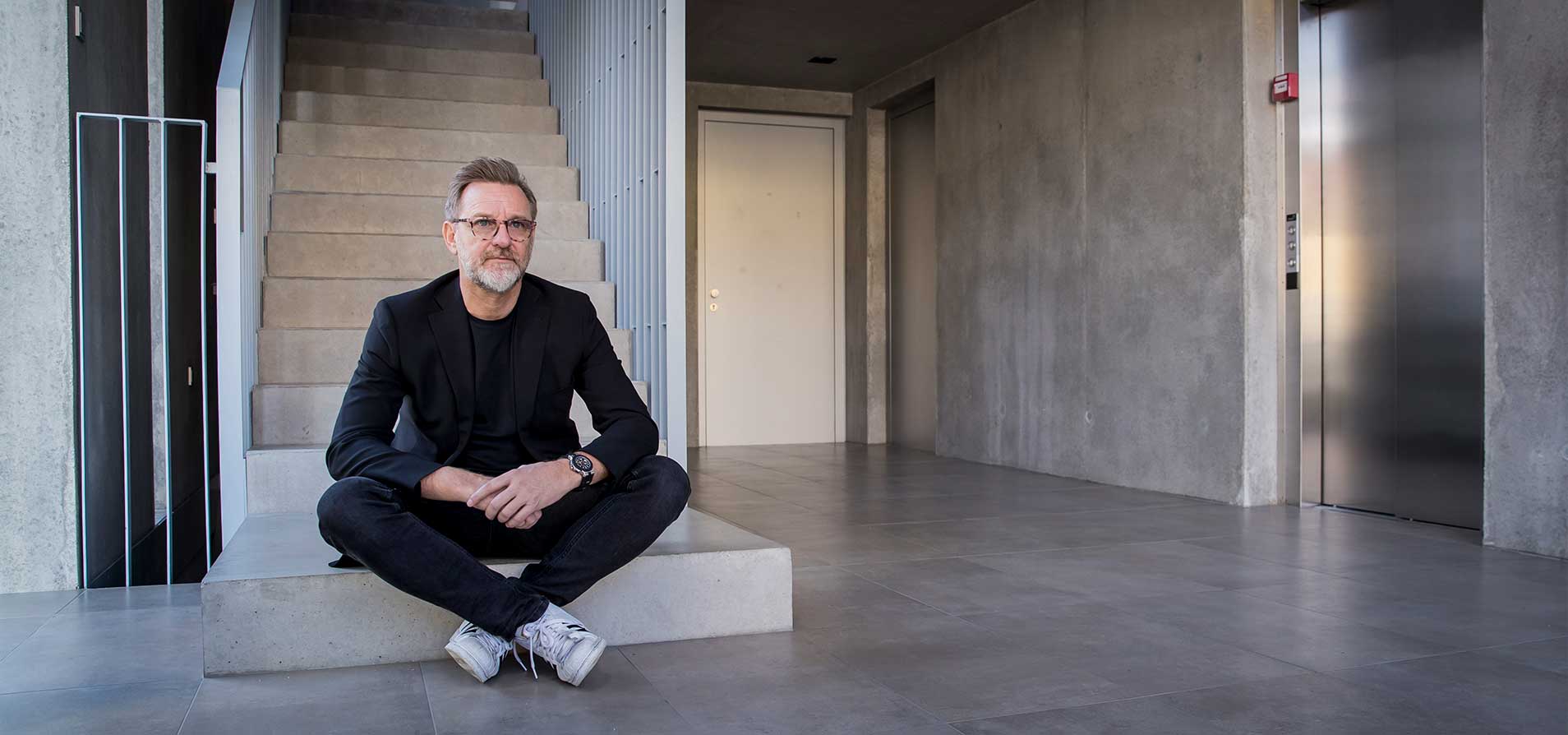 Ein Mann sitzt auf einer Treppe in einem modernen Gebäude.