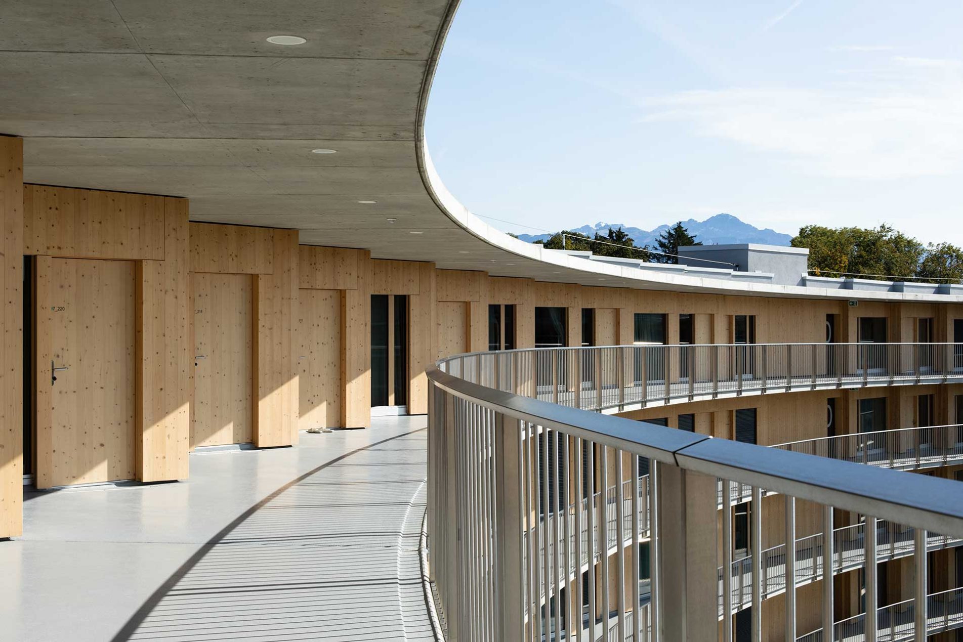 Kurvenförmiger Balkon mit Holzverkleidung und Geländer.