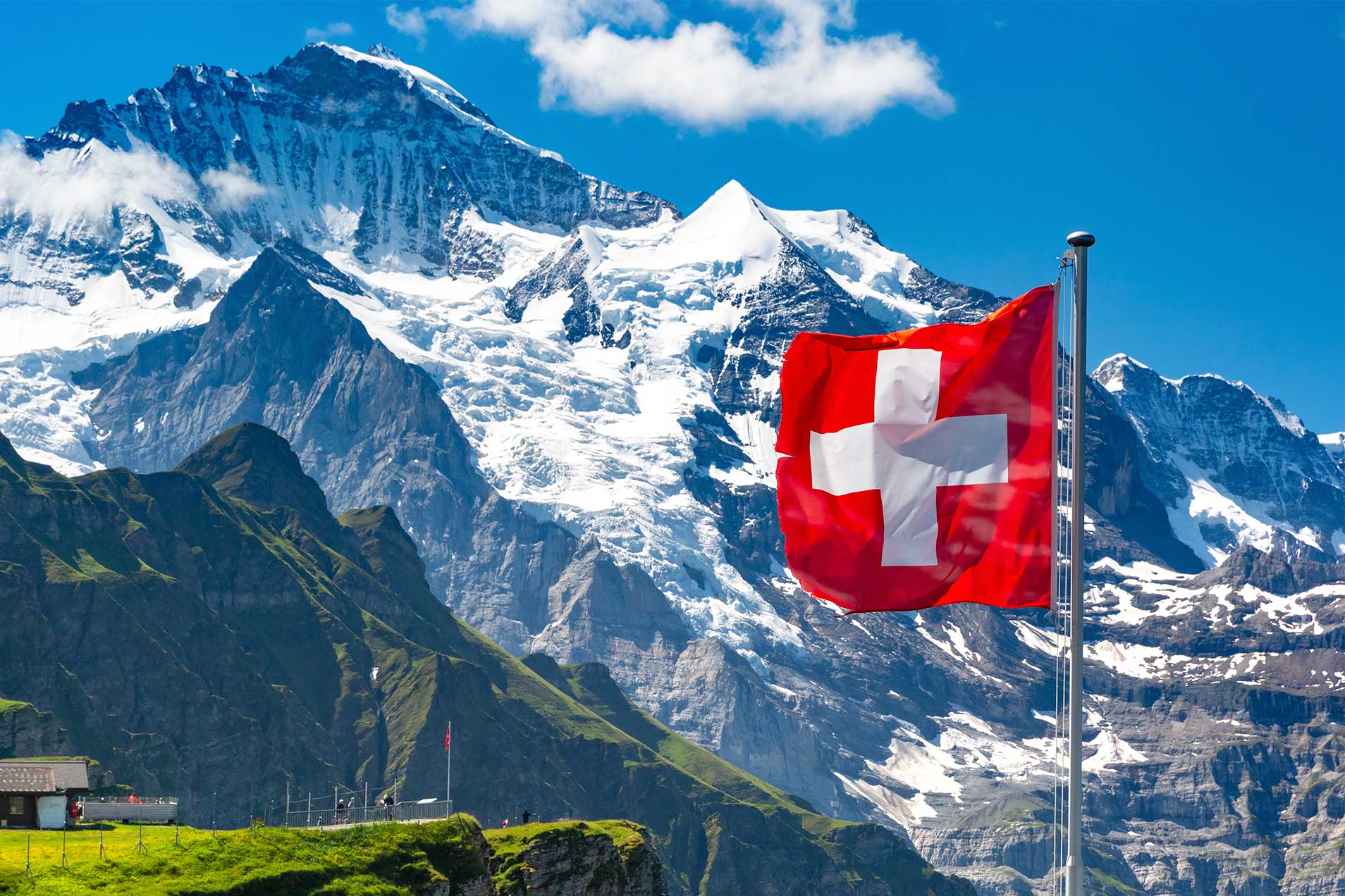 Wackelnde Schweizer Flagge vor Berglandschaft.