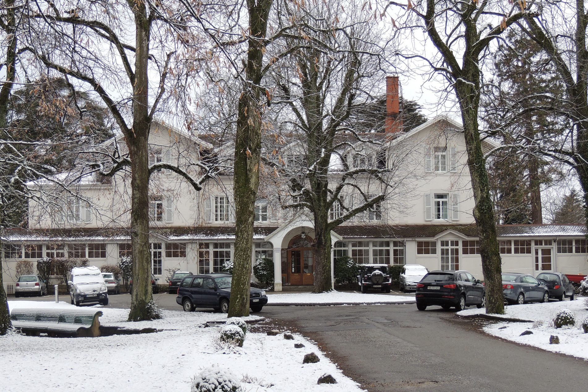 Grosses Herrenhaus umgeben von Schnee und Bäumen.