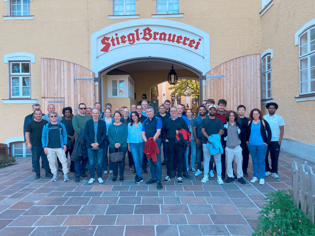 Freundliche Gruppe vor einer Brauerei bei Abendlicht.