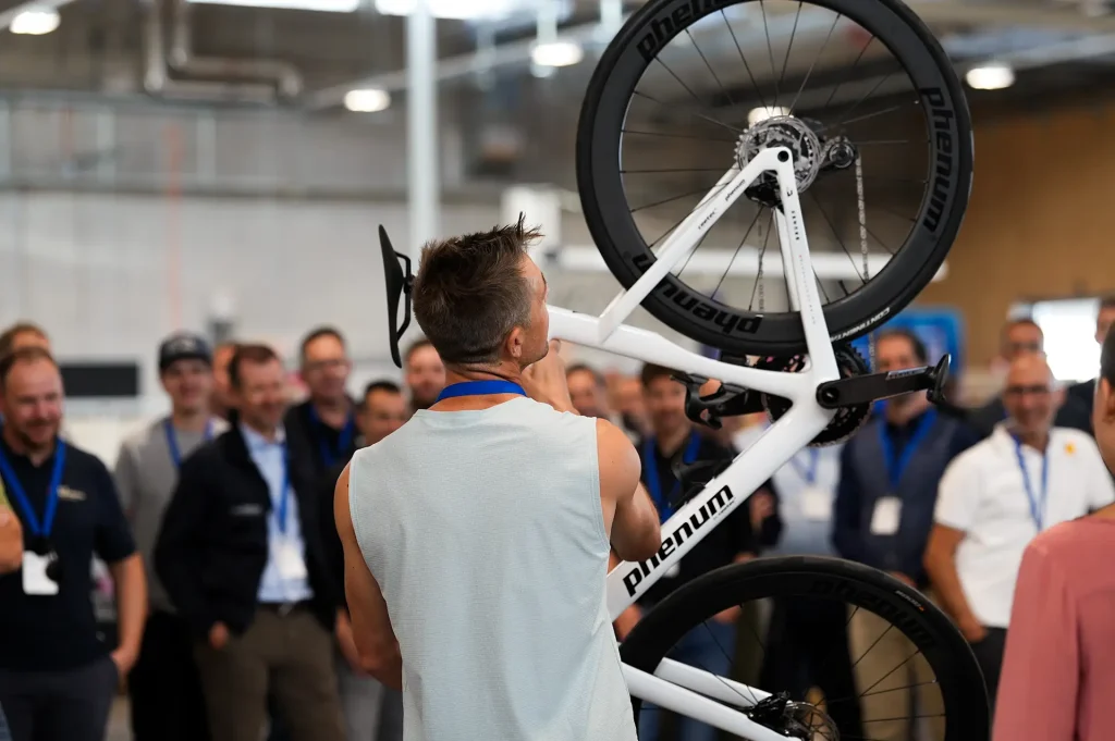 Eine Person hebt ein Fahrrad vor einer Gruppe von Zuschauern.